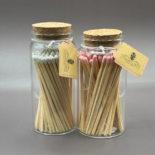 Two apothecary jars on a grey background filled with white and pink tipped matches.