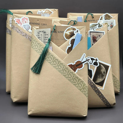 Books stacked in front of a grey background wrapped in paper with bookmarks and stickers stuffed into the folds.